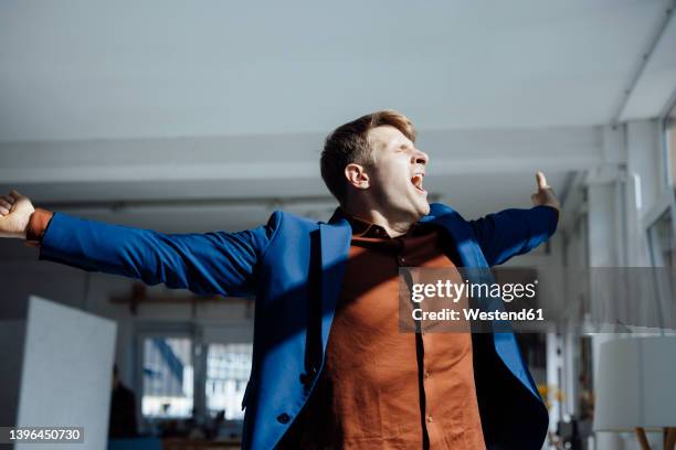 businessman with arms outstretched yawning in office - yawn office stock-fotos und bilder