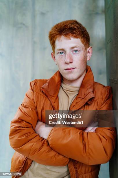 redhead boy with arms crossed leaning on wall - redhead boy stock pictures, royalty-free photos & images