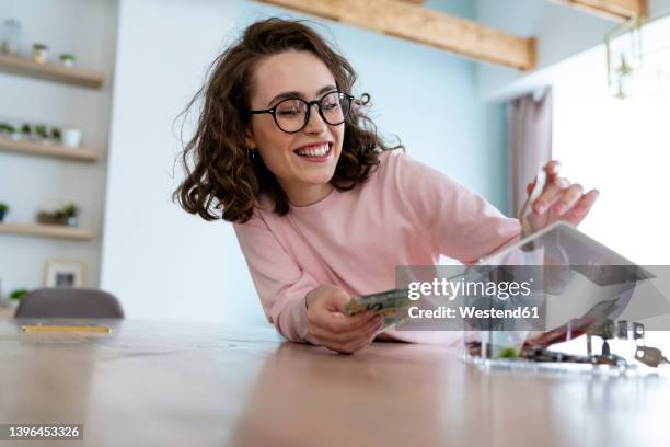 happy woman saving money in piggy bank at home - savings fotografías e imágenes de stock