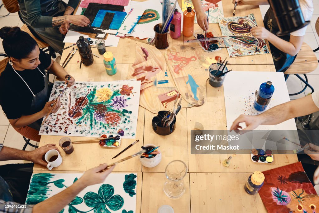 High angle view of students practicing painting at table in art class