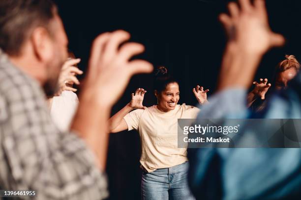 happy actress gesturing while rehearsing with stage performers in class - woman theatre stock-fotos und bilder