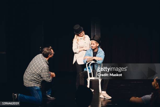 instructor looking at man and woman wearing hat rehearsing on stage - acting fotografías e imágenes de stock