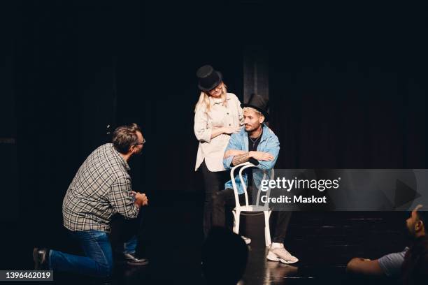 instructor looking at man and woman wearing hat rehearsing on stage - acting foto e immagini stock