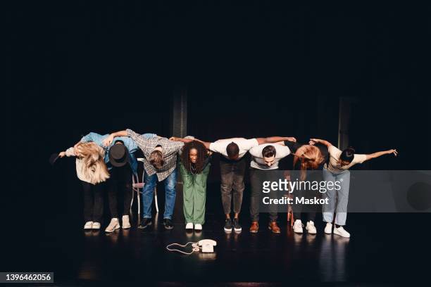 full length of multiracial male and female artists bowing together on stage - schauspieler stock-fotos und bilder
