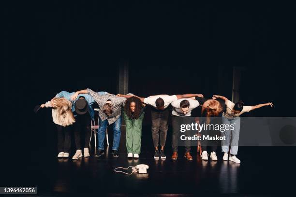 full length of multiracial male and female artists bowing together on stage - end of play stockfoto's en -beelden