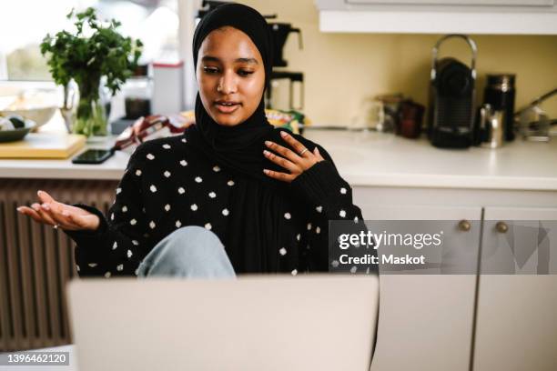 young female freelancer gesturing during video call through laptop at home - veil stock pictures, royalty-free photos & images