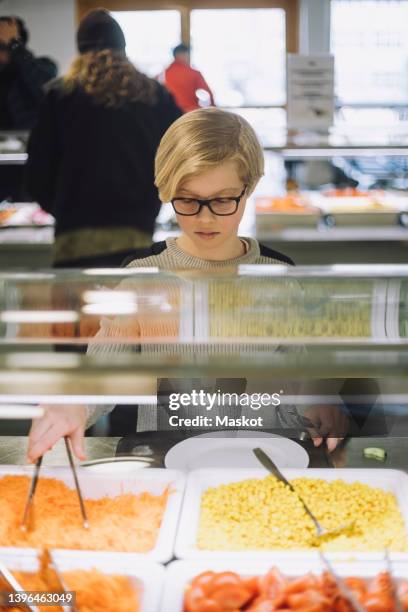 boy taking food during lunch break in cafeteria - salad bar stock pictures, royalty-free photos & images