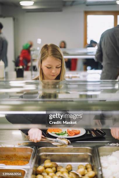 girl taking food from food bar during lunch break in cafeteria - salad bar stock pictures, royalty-free photos & images