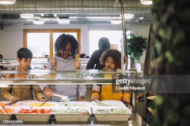 friends talking while taking food during lunch break in cafeteria - kantine stock-fotos und bilder