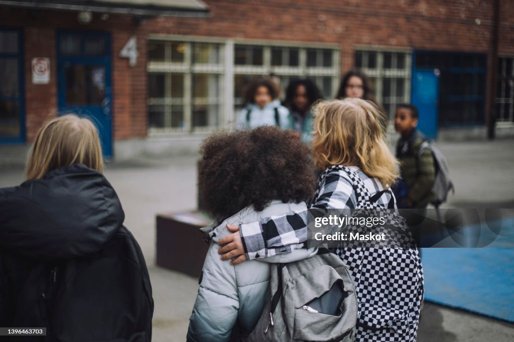 Boy walking with arm around friend in school campus