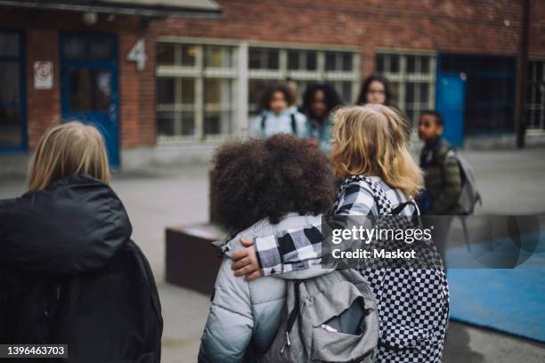 boy walking with arm around friend in school campus - leerling stockfoto's en -beelden