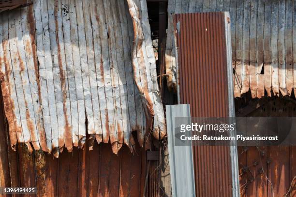 closeup old damaged corrugated rusty iron roof and facade - corrugated stock pictures, royalty-free photos & images