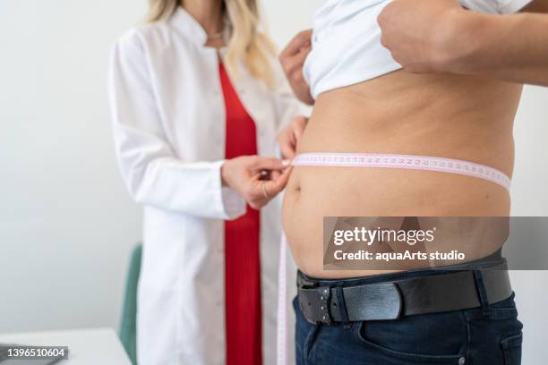 waist measurement - doctor with patient man stockfoto's en -beelden