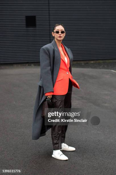 Betty Bachz wears a David Koma coat, blazer, trousers and bag, Christian Louboutin shoes and Moy Atelier sunglasses during London Fashion Week...