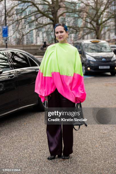 Guest wears a Roksanda Ilincic top, dark purple silk trousers, black bag and Maison Margiela boots during London Fashion Week February 2022 on...