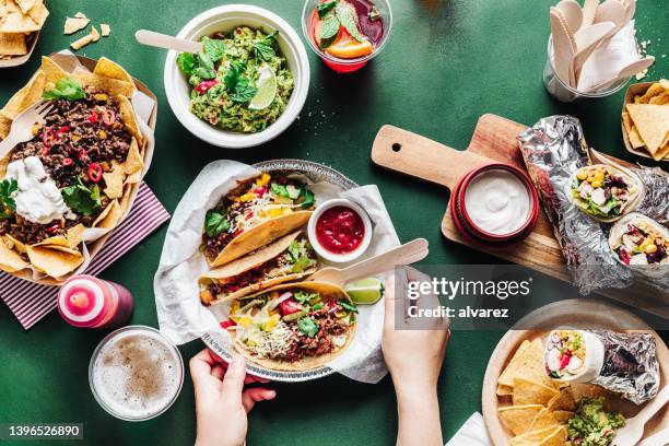 close-up of a woman serving mexican food and fajitas on green table - taco stockfoto's en -beelden