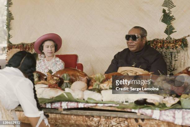 Queen Elizabeth II sits down to a Maori banquet during her visit to New Zealand, 1977.
