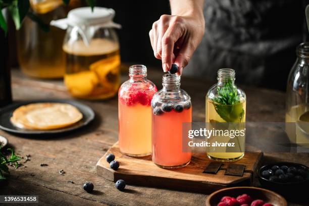 close-up of a woman preparing flavored kombucha tea in kitchen - kombucha stockfoto's en -beelden