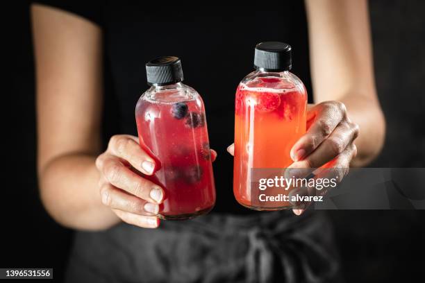 close-up of woman hands holding two bottles of kombucha tea - kombucha stock pictures, royalty-free photos & images