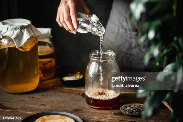 woman making healthy probiotic drink at home - kombucha stockfoto's en -beelden