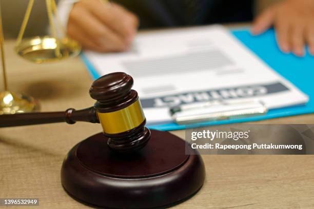 male judge working with contract papers on wooden table in courtroom. justice and law concept - government contract stock pictures, royalty-free photos & images