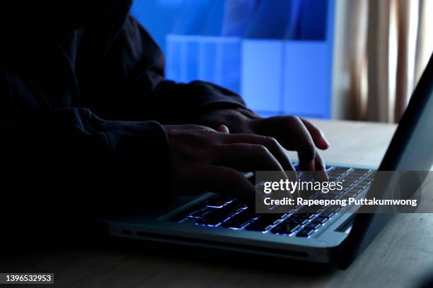 hacker working on laptop at night under blue light. - ransomware fotografías e imágenes de stock
