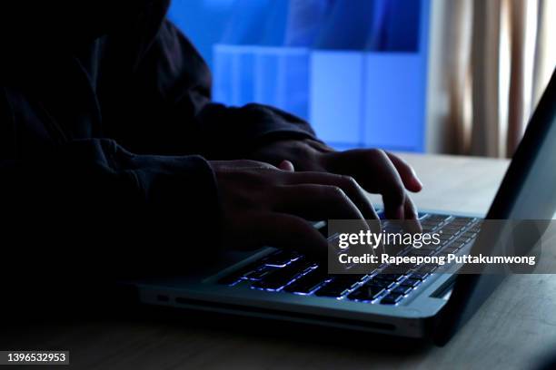 hacker working on laptop at night under blue light. - phishing fotografías e imágenes de stock