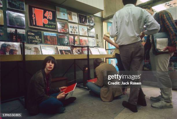 View of American Rock musician Todd Rundgren sits on the floor at the Record Mart, Philadelphia, Pennsylvania, June 1967. He holds a copy of the...