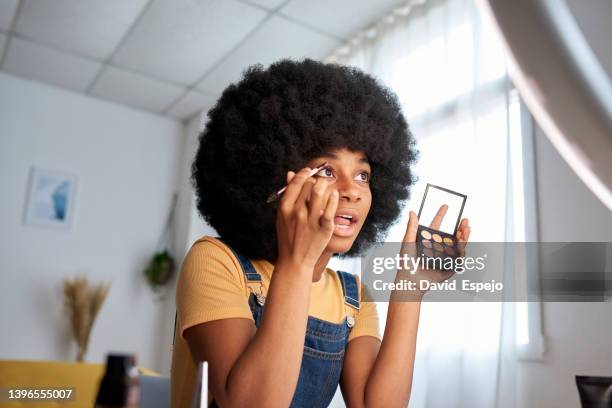 view of an afro woman holding a make-up palette while painting her eyebrows. - make up imagens e fotografias de stock