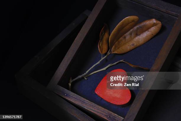 weathered red wooden heart and dried leaves inside a wooden box on dark background - memories box stock pictures, royalty-free photos & images
