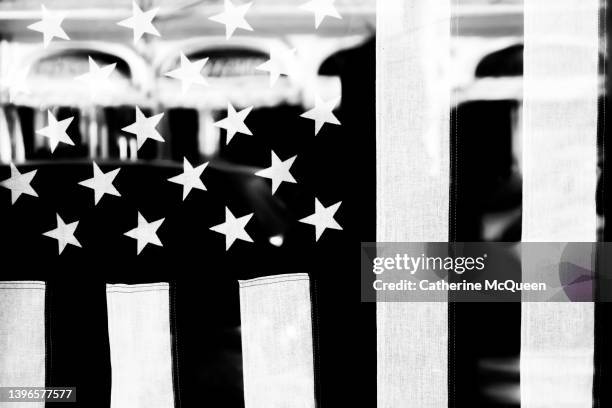american flag hanging vertically in glass door of commercial storefront - usa flag black and white stock pictures, royalty-free photos & images