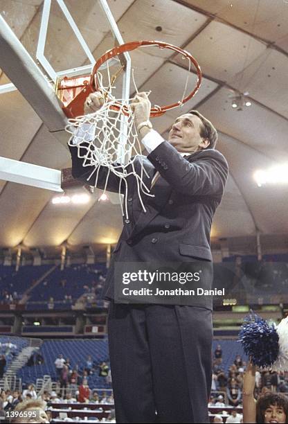 Coach Mike Krzyzewski of the Duke Blue Devils cuts the net after winning a playoff game against the Michigan Wolverines at the Hubert H. Humphrey...