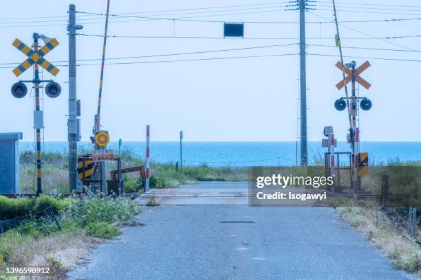 a railroad crossing with a view of the sea - koshin'etsu region photos et images de collection