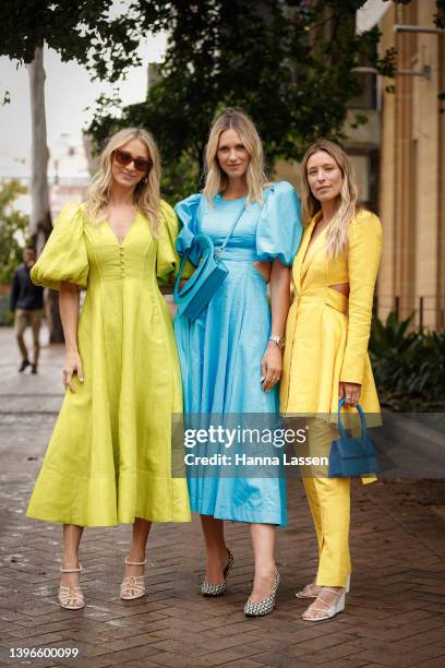Anna Heinrich wearing yellow Aje dress, Nikki Phillips wearng blue Aje dress and Jacquemus blue bag at Afterpay Australian Fashion Week 2022 on May...