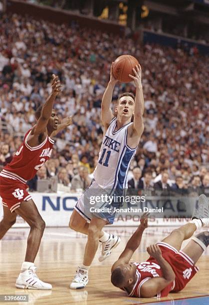 Guard Bobby Hurley of the Duke Blue Devils drives between guard Greg Graham and Damon Bailey of the Indiana Hoosiers during a playoff game at the...