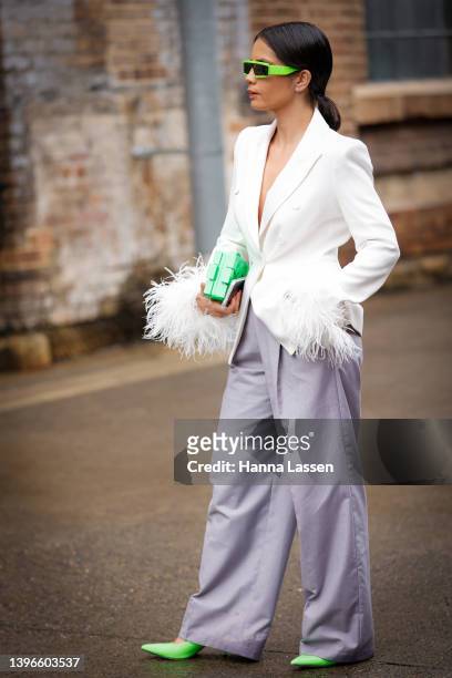 Guest wearing neon skinny sunglasses, white jacket and lavender wide pants at Afterpay Australian Fashion Week 2022 on May 11, 2022 in Sydney,...