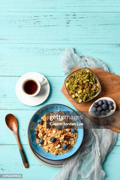 granola with almonds and blueberries on turquoise colored background - blue bowl foto e immagini stock