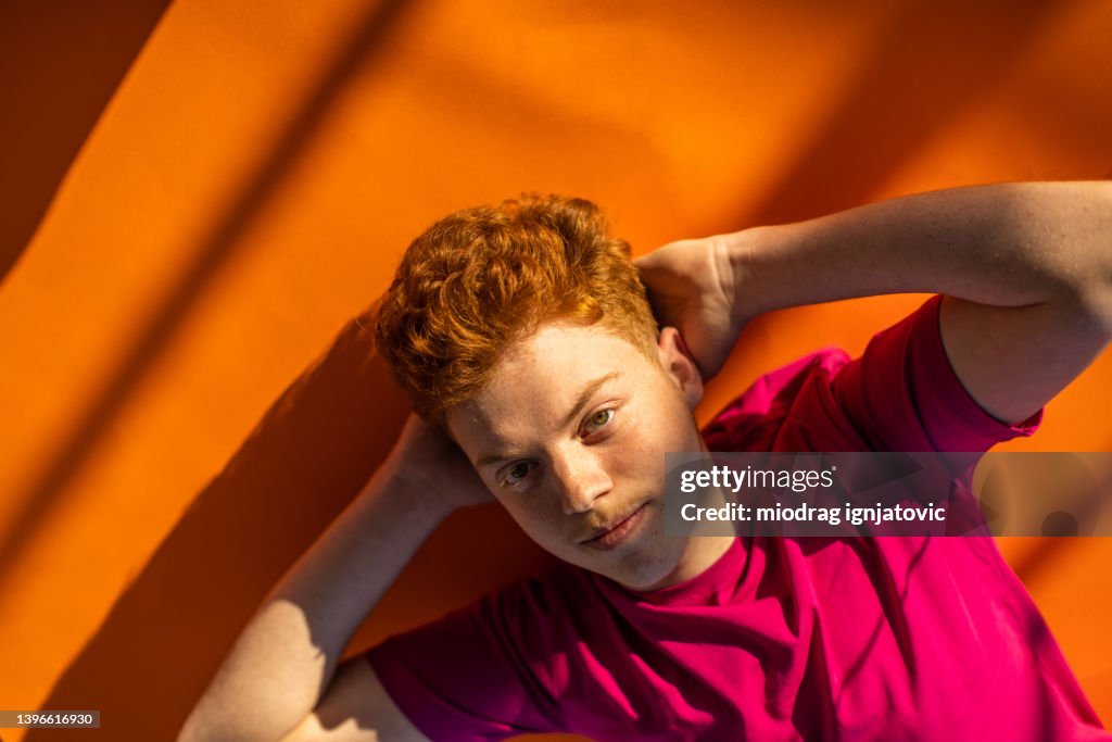 Caucasian redhead teenage boy lying on the floor and relaxing