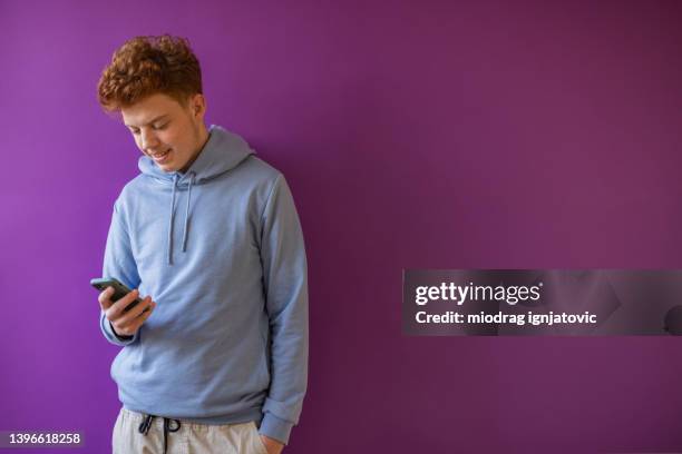 adolescente pelirrojo caucásico usando teléfono móvil - chico adolescente fotografías e imágenes de stock