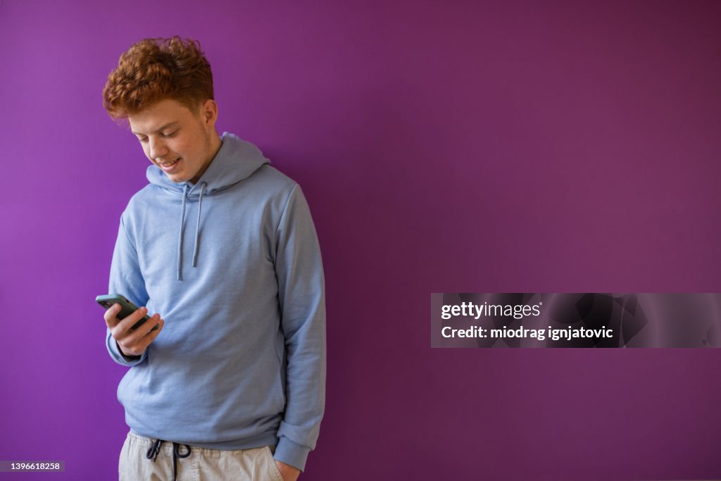 Caucasian redhead teenage boy using mobile phone