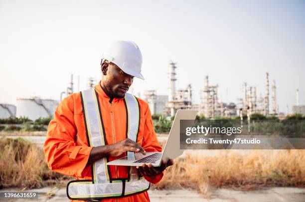 african construction engineer working on laptop reviewing build project in the industrial area. - industria petrolifera foto e immagini stock