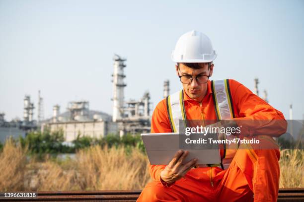 caucasian engineer working with tablet reviewing build project in the industrial area. - gas plant stock pictures, royalty-free photos & images