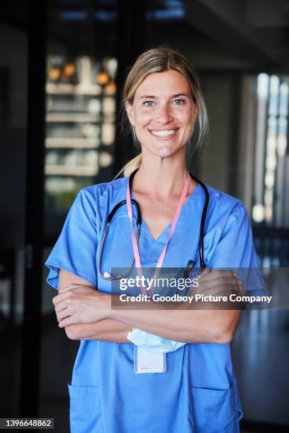 smiling young female doctor wearing scrubs standing in a hospital - skill stock pictures, royalty-free photos & images