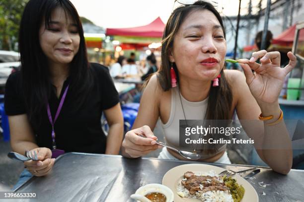 woman eating a chili pepper at a street food stall in chiang mai - chili woman ストックフォトと画像