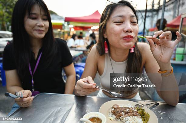 woman eating a chili pepper at a street food stall in chiang mai - eating cereal stock pictures, royalty-free photos & images