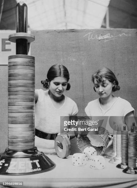 Two women throwing three large dice from a basket while playing 'Be-Zett' at the Concours Lepine, the annual show of craftspeople and inventors in...