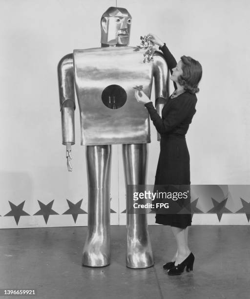 Musician Lois Kendall decorates mechanical man Elektro with leaves as part of a Westinghouse Electric & Manufacturing Company's demonstration at the...