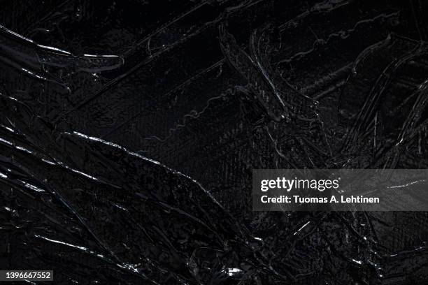 macro close-up of glossy black acrylic paint on canvas. - black acrylic texture stock pictures, royalty-free photos & images