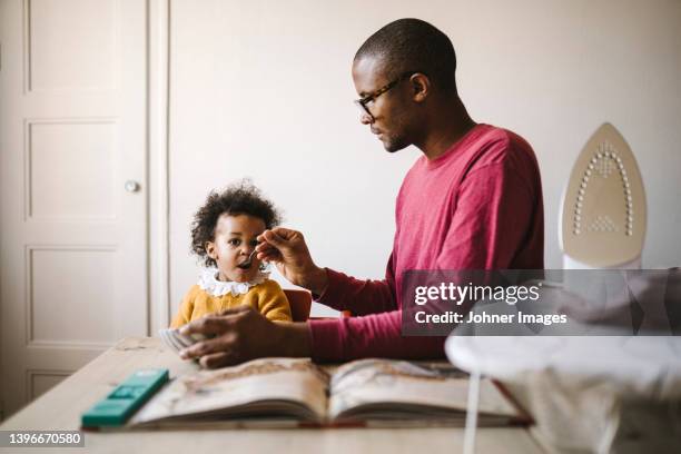 father feeding girlfriend from bowl - parental leave stock pictures, royalty-free photos & images