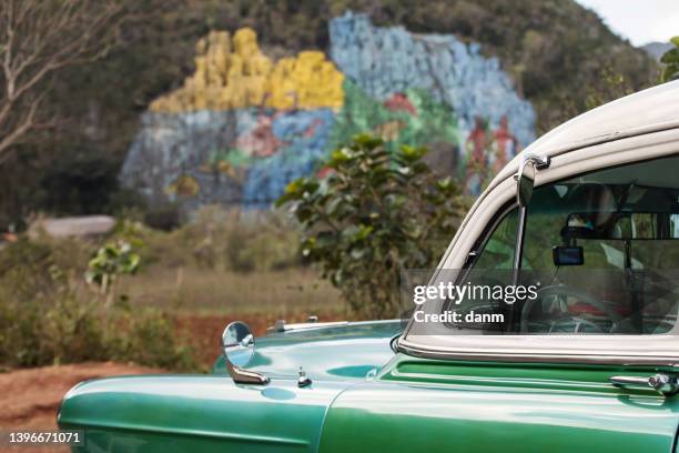 old american car with colourful mural wall from vinales, cuba - prehistoria stock pictures, royalty-free photos & images